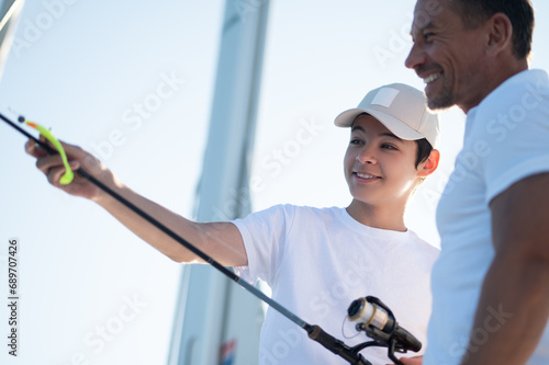 Teen and his dad on a yacht with a fishing rod