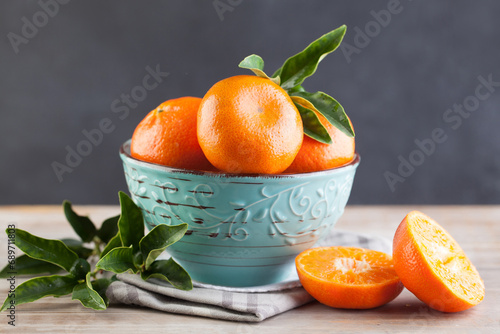 Bowl with orange tangerine fruit on brown wood, healthy food background