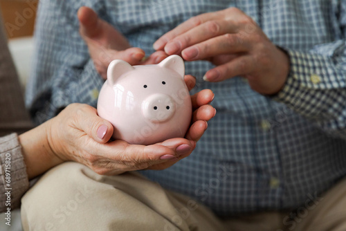 Saving money investment for future. Senior adult mature couple hands putting money coin in piggy bank. Old man woman counting saving money planning retirement budget. Saving investment banking concept