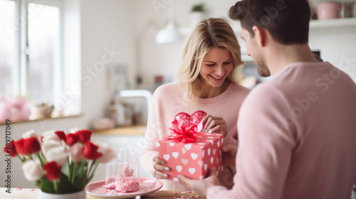 Couple in love in the kitchen exchanges homemade gifts in honor of Valentine's Day. A man and a woman spend time together at home. Concept of love, holiday. photo