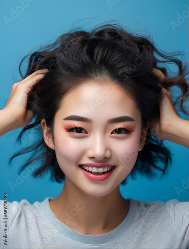 Beautiful young Asian woman with clean fresh skin and touching Hair, Enjoying the freedom a blue background 