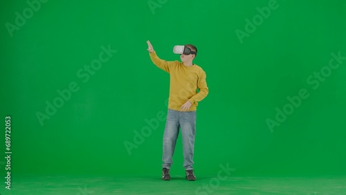 Portrait of kid boy on chroma key green screen. Schoolboy in jeans wears virtual reality glasses amazed face expression. Full body front shot. © kinomaster