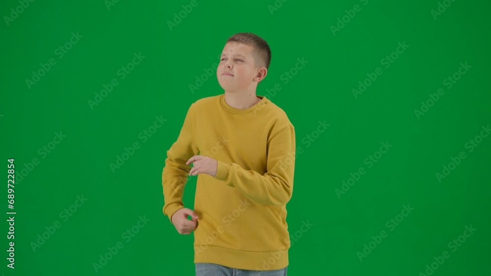 Portrait of kid boy on chroma key green screen. Schoolboy in jeans running looking around. Middle body front shot. Portrait of kid boy on chroma key green screen. Schoolboy in jeans running looking around. Middle body front shot.