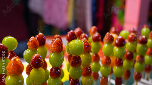 Fototapeta Naklejka Na Ścianę i Meble -  Pictures of sweet street food menus at temple fairs This menu is fruit skewers. It consists of large green grapes. and small strawberries skewered and drizzled with syrup.