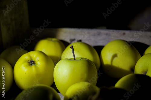 Ripe organic grown apples in wooden box in bright light.