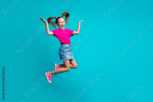 Full size photo of optimistic girl dressed pink t-shirt skirt palms demonstrate offer empty space isolated on turquoise color background © deagreez