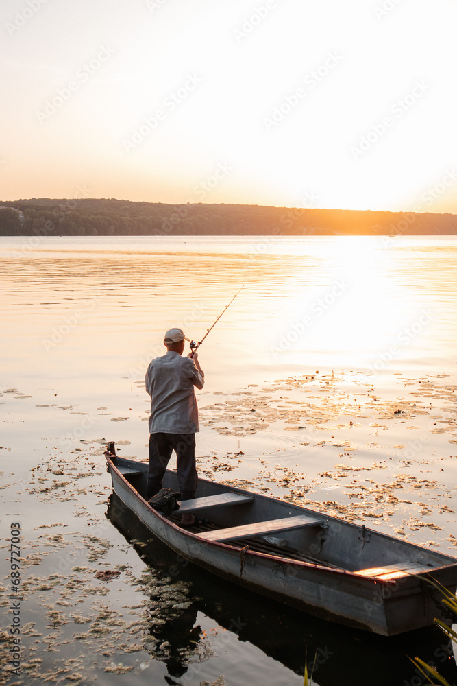 man shot from behind fishing on a boat at sunset man shot from behind fishing on a boat at sunset