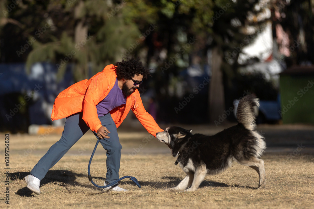 Young Mexican boy with curly hair, playing with a husky dog in a park and whit a leash in the hand Young Mexican boy with curly hair, playing with a husky dog in a park and whit a leash in the hand
