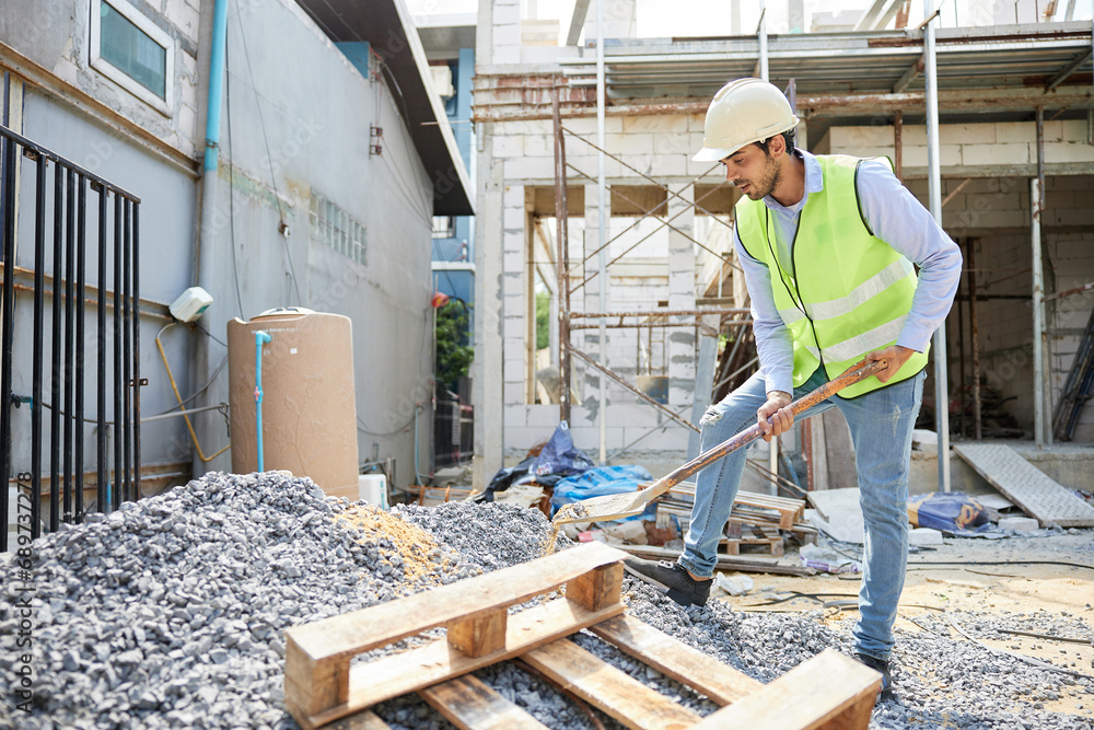 Fototapeta premium construction worker using shovel and digging sand at construction site