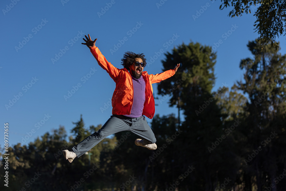 Young Mexican man jumping in the air with his arms wide open, happiness and success concept Young Mexican man jumping in the air with his arms wide open, happiness and success concept