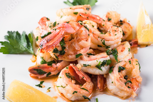Foto Fried Argentine shrimps with garlic and herbs on a white plate with lemon