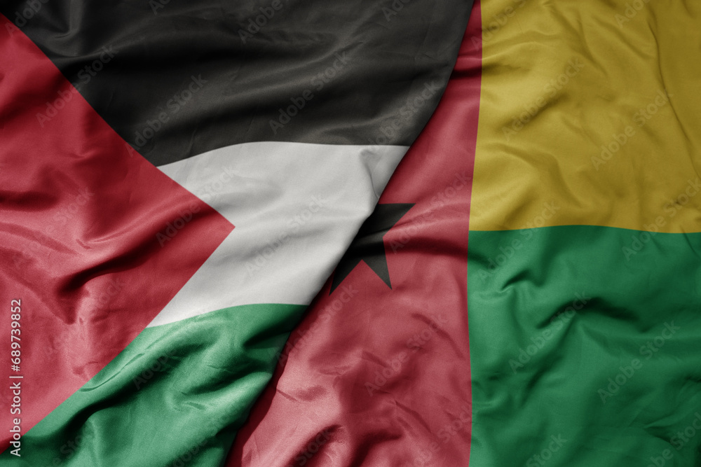 big waving national colorful flag of guinea bissau and national flag of palestine .
