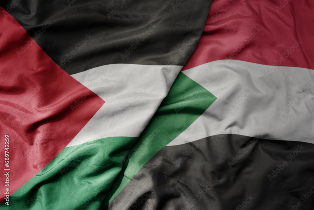 big waving national colorful flag of sudan and national flag of palestine .