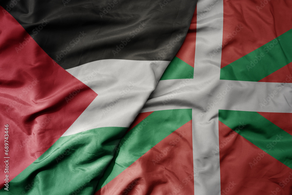 big waving national colorful flag of basque country and national flag of palestine .