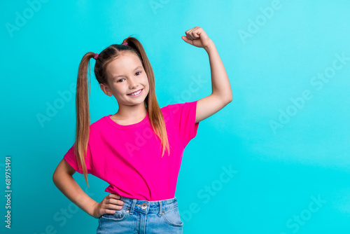 Photo of glad adorable cute girl wear stylish pink clothes showing muscular arm empty space isolated on cyan color background