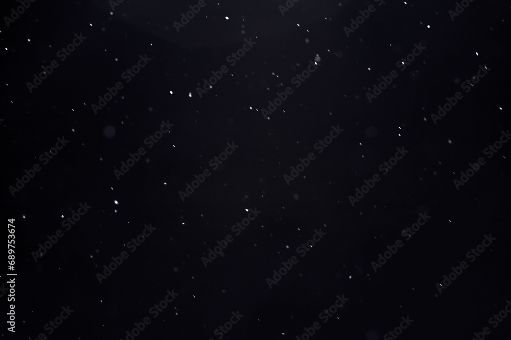 blurred winter snow background with flying snowflakes against black sky, texture for overlay and design