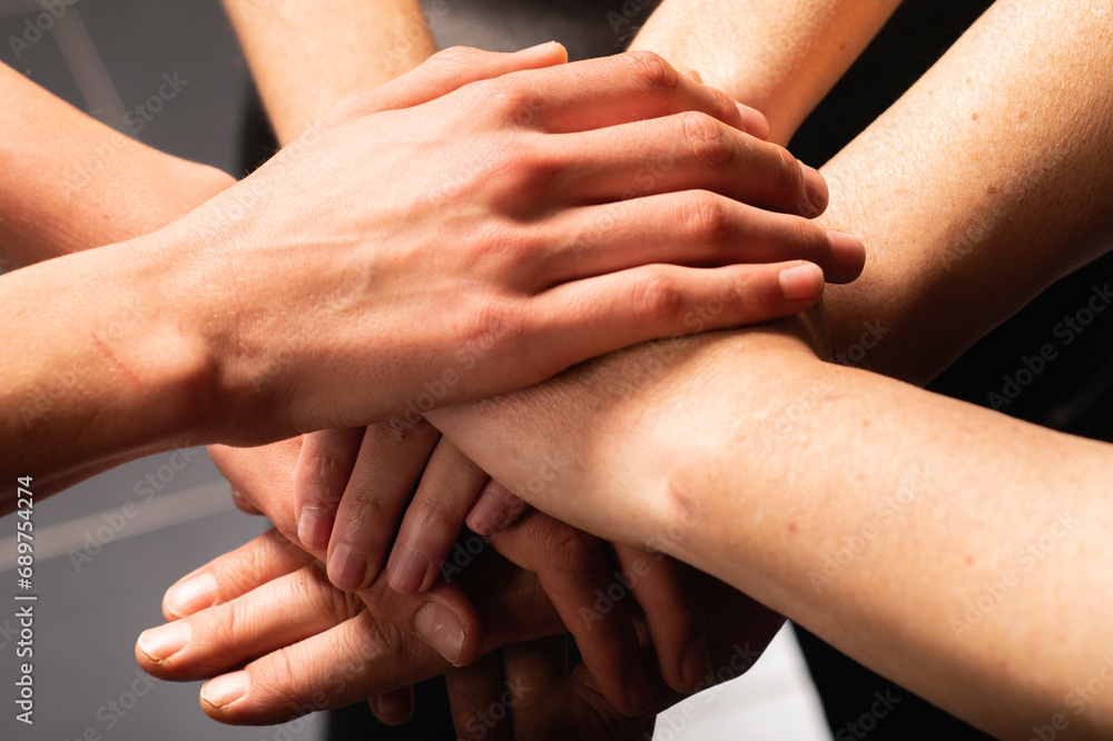 Friends with stack of hands showing unity and teamwork Friends with stack of hands showing unity and teamwork