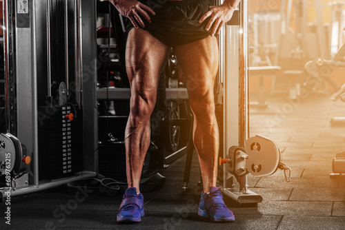 Closeup image of a strong man with muscular legs . posing at gym photo