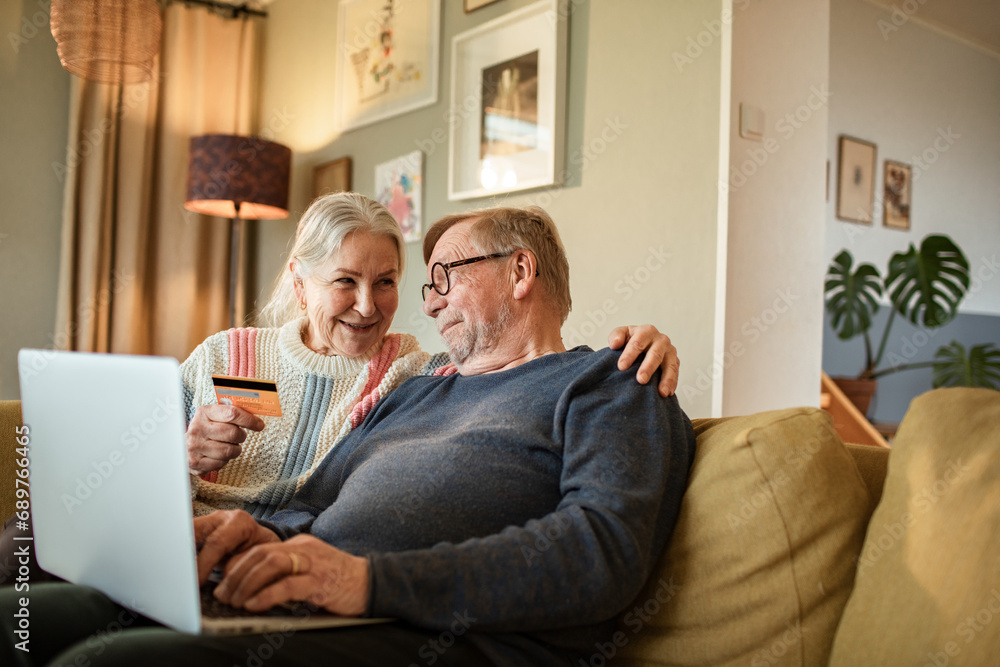 Happy senior couple paying with credit card on laptop at home Happy senior couple paying with credit card on laptop at home