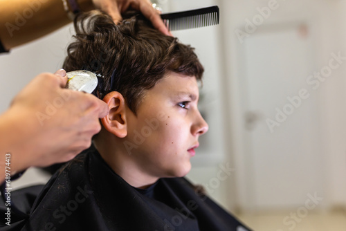 Cute young boy getting a haircut by hairdresser