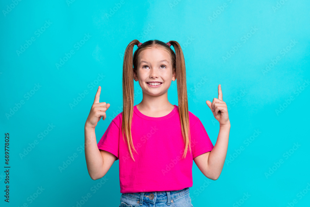 Portrait of charming little girl look direct fingers up empty space ad banner isolated on turquoise color background Portrait of charming little girl look direct fingers up empty space ad banner isolated on turquoise color background