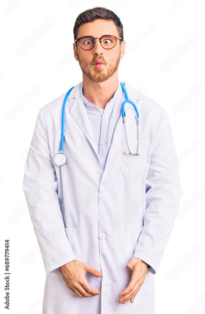 Fototapeta premium Handsome young man with bear wearing doctor uniform making fish face with lips, crazy and comical gesture. funny expression.