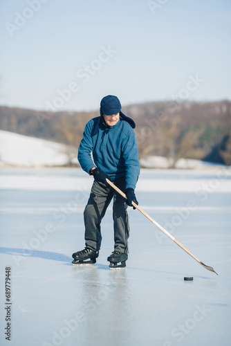 Photography An elderly man practices ice hockey on a frozen lake in winter.