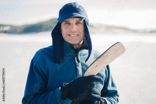 Photography Elderly man with a hockey stick on a frozen lake in winter