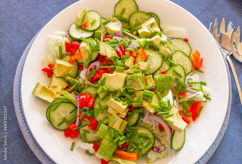 fresh green salad with cucumber, avocado, onions and lettuce on white plate fresh green salad with cucumber, avocado, onions and lettuce on white plate
