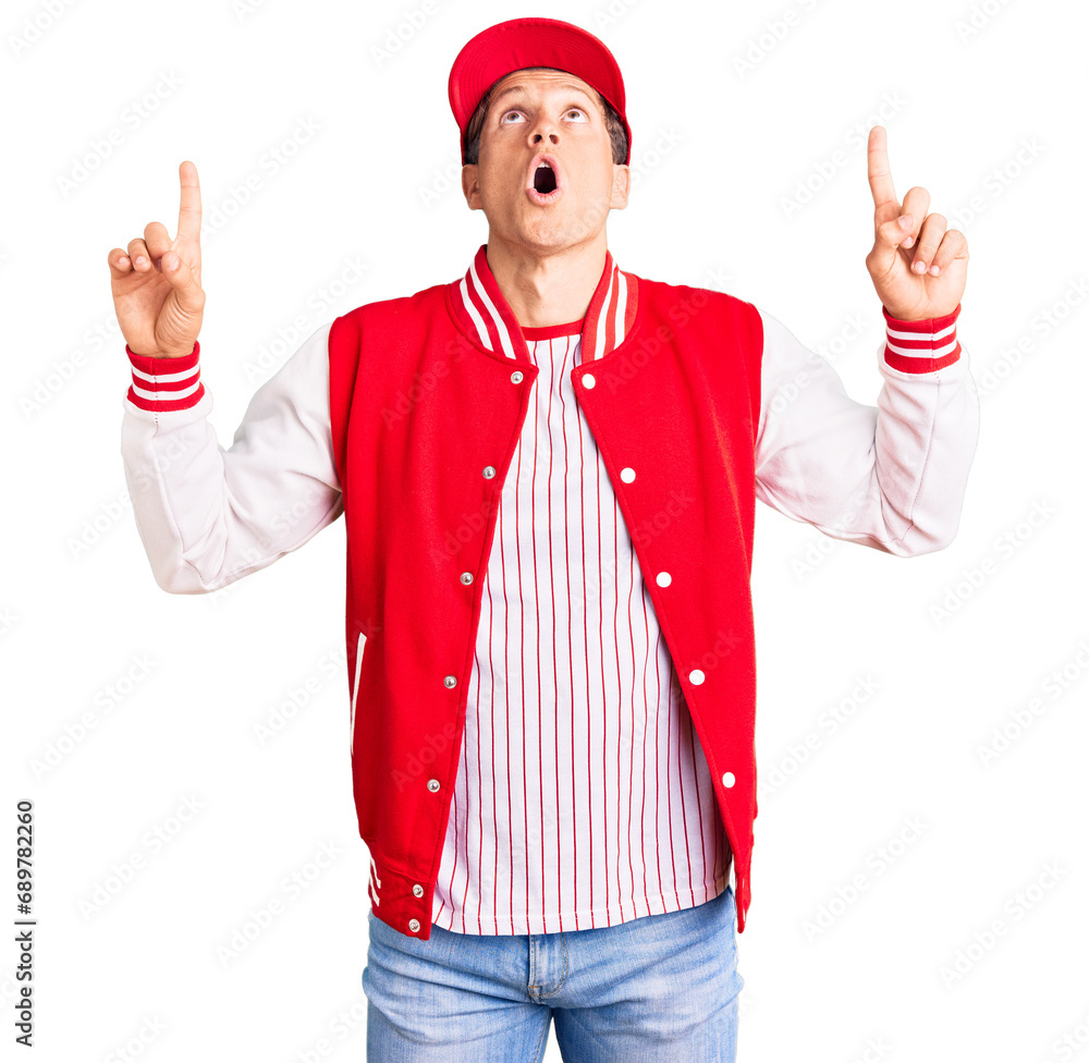 Young handsome man wearing baseball uniform amazed and surprised looking up and pointing with fingers and raised arms. Young handsome man wearing baseball uniform amazed and surprised looking up and pointing with fingers and raised arms.