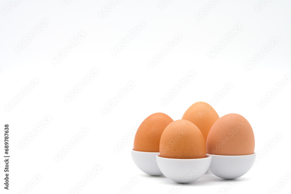 Four chicken eggs in different sizes in egg holders isolated on a white background Four chicken eggs in different sizes in egg holders isolated on a white background
