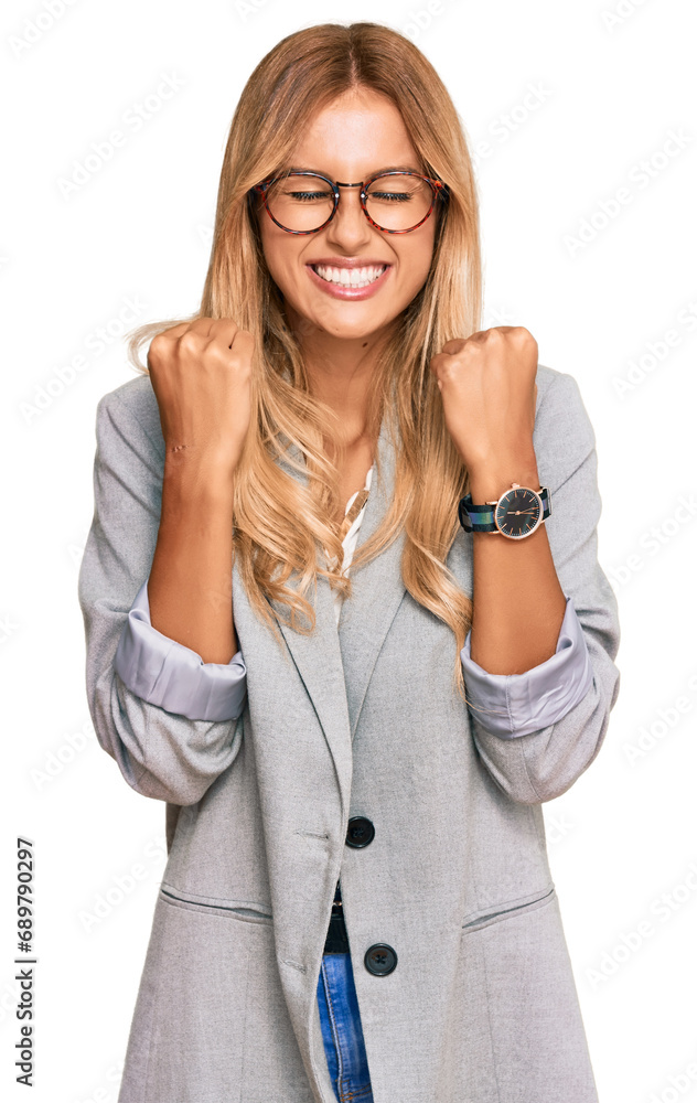 Beautiful blonde young woman wearing business clothes excited for success with arms raised and eyes closed celebrating victory smiling. winner concept. Beautiful blonde young woman wearing business clothes excited for success with arms raised and eyes closed celebrating victory smiling. winner concept.
