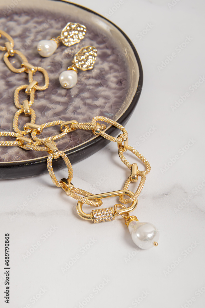 Pearl earrings and a gold chain necklace. Costume jewelry set closeup Pearl earrings and a gold chain necklace. Costume jewelry set closeup