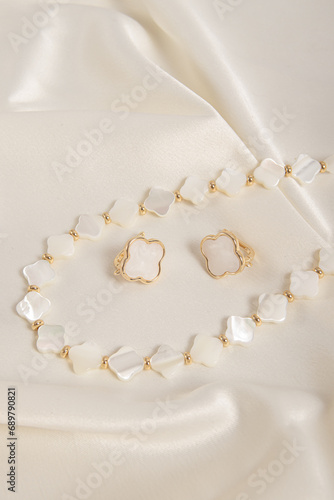 Set of jewelry made of mother of pearl. Necklace and earrings on silk background