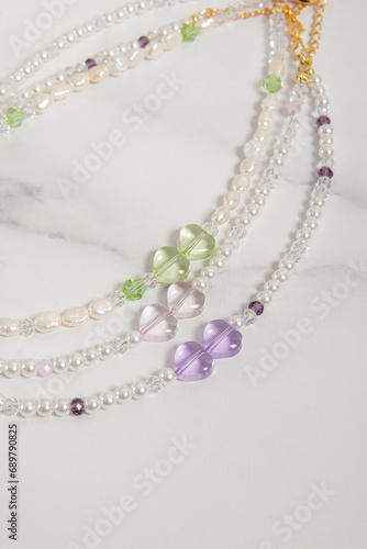 Three pearl chokers with hearts beads on marble background