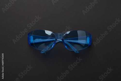 Safety glasses on color background, top view