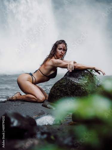 Attractive young woman with posing with powerfull waterfall