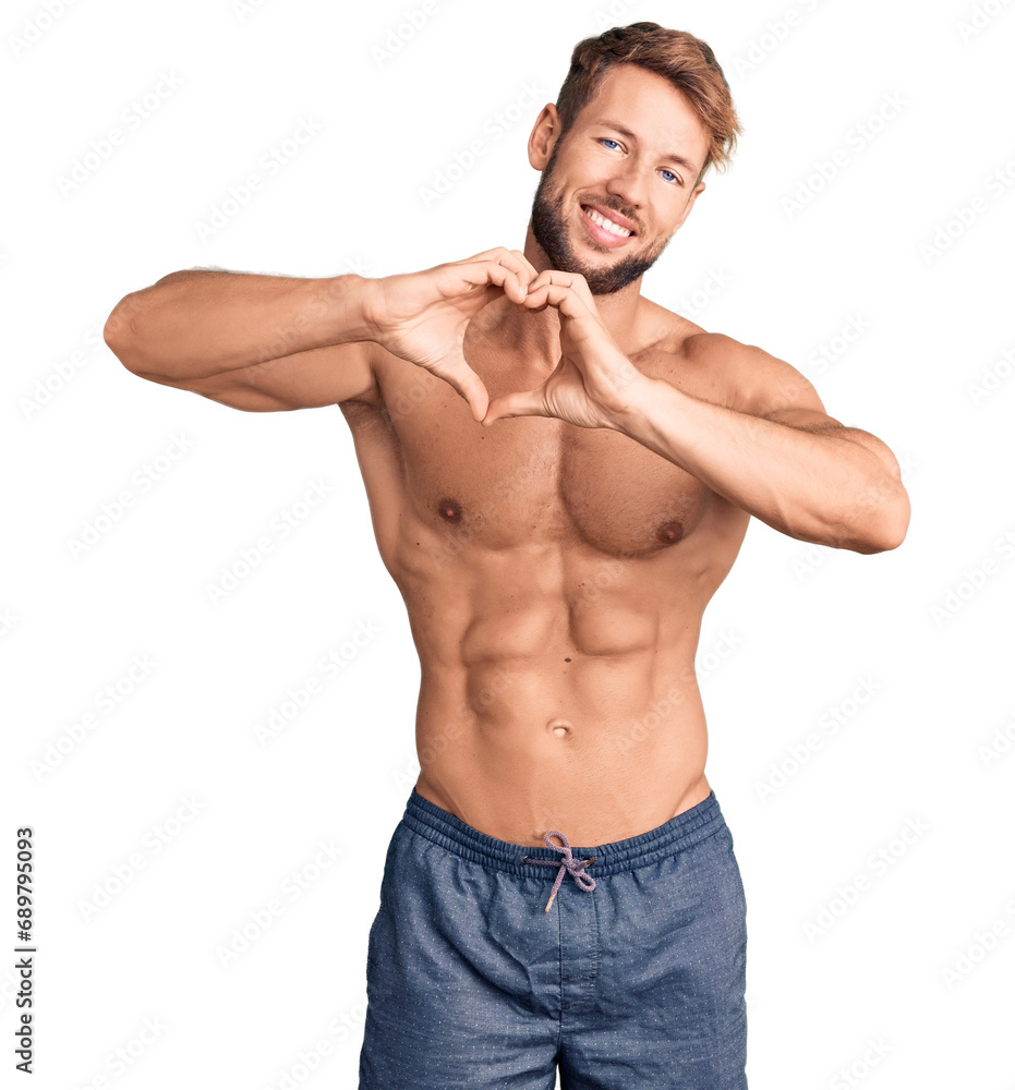 Fototapeta premium Young caucasian man standing shirtless smiling in love doing heart symbol shape with hands. romantic concept.