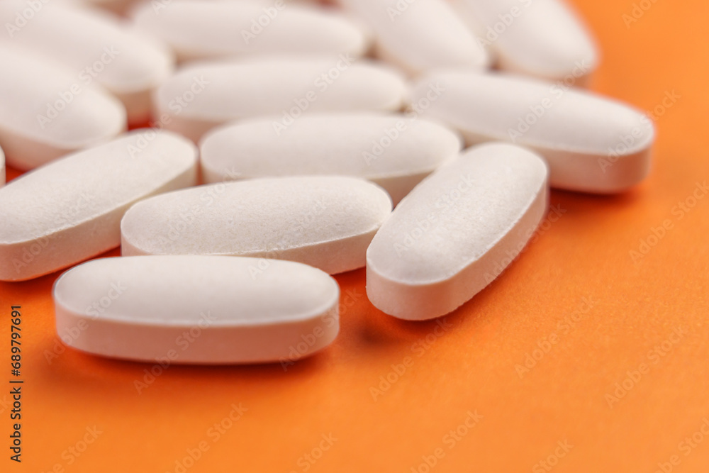 White tablets on an bright orange background. Alternative medicine concept. Healing pills. White tablets on an bright orange background. Alternative medicine concept. Healing pills.