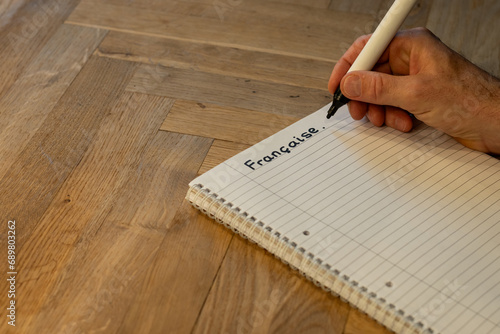 Blank notepad in class on wooden desk for student learning French written language. Française subject for adult learning with handwritten notes and writing exercises for personal development 