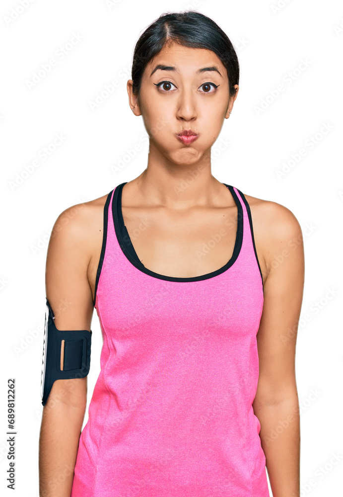Beautiful asian young sport woman wearing sportswear and arm band puffing cheeks with funny face. mouth inflated with air, crazy expression. Beautiful asian young sport woman wearing sportswear and arm band puffing cheeks with funny face. mouth inflated with air, crazy expression.