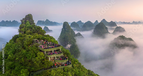 Aerial view of a lookout point terrace on the mountain top looking the Guilin mountain landscape at sunrise with low clouds, Guangxi, China.
