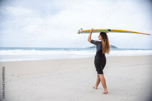 Mulher jovem na praia segurando sua prancha se surf acima de sua cabeca. photo