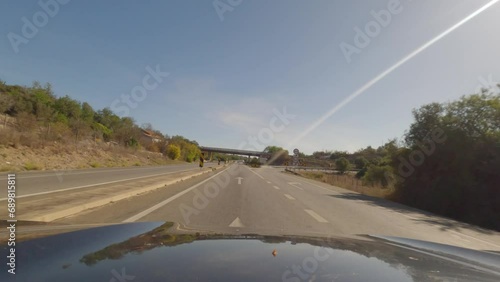 First person view, FPV, from dashcam of car driving along the Algarve Coast in Portugal outside of Portimao towards the Benagil Caves, driving on the highway. Road trip video in POV, with blue sky photo