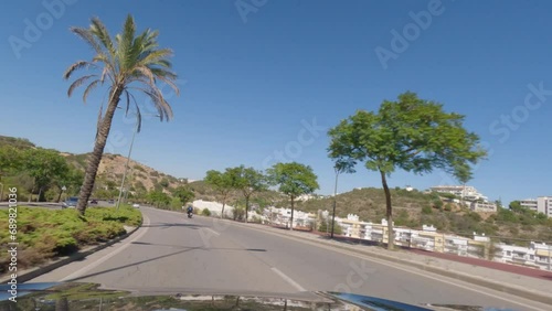 First person view, FPV, from dashcam of car driving along the Algarve Coast in Portugal in Albufeira, driving in the city. Road trip video in POV, with blue sky photo