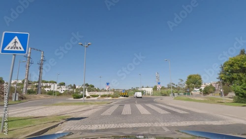 First person view, FPV, from dashcam of car driving along the Algarve Coast in Portugal towards Albufeira, driving on the highway. Road trip video in POV, with blue sky photo