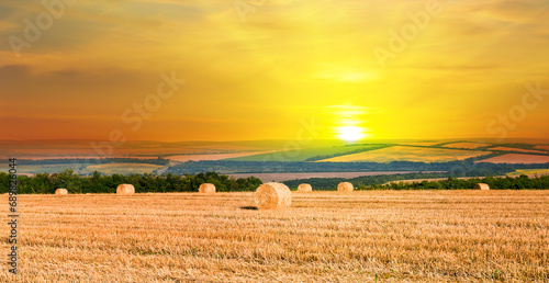 A field with haystacks on an autumn evening with a cloudy sky in the background at sunset . Wide photo.
