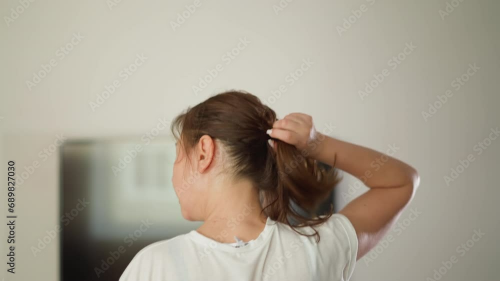 Running woman pulls down hair at home. Sportive lady in white t-shirt jogs with waving loose hair in domestic gym. Exercising for wellbeing Running woman pulls down hair at home. Sportive lady in white t-shirt jogs with waving loose hair in domestic gym. Exercising for wellbeing