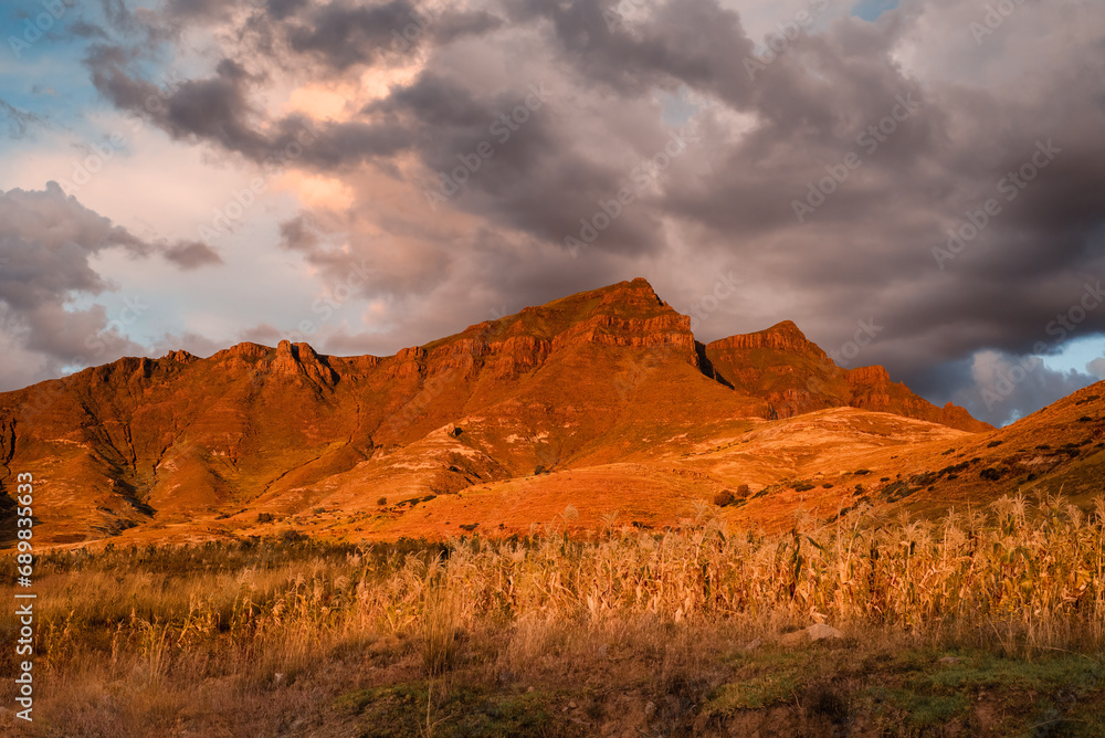 Red sunlit mountain at sunset under stormy skies in Lesotho