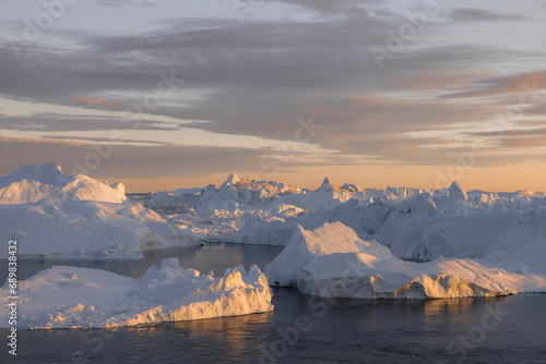 View of icebergs and floes at the disco bay ice fjord with golden light in Ilulissat, Greenland. photo